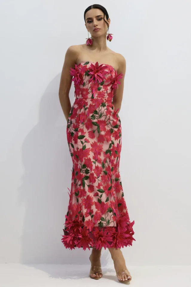 Woman wearing a pink strapless midi dress with floral embellishments and a trumpet skirt.