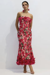 Woman wearing a pink strapless midi dress with floral embellishments and a trumpet skirt.