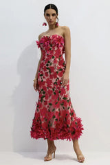 Woman wearing a pink strapless midi dress with floral embellishments and a trumpet skirt, posing.