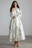 Woman wearing a white floral print chiffon tiered midi dress with long bishop sleeves and a high neckline.