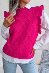 Close-up of a woman wearing a bright pink cable knit sweater vest with ruffled shoulders over a white collared shirt.