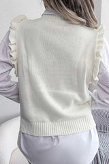 Back view of a woman wearing a white cable knit sweater vest with ruffled shoulders over a white collared shirt.