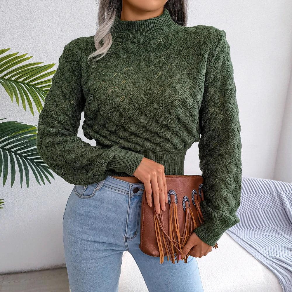 Front view of a woman wearing a green mock neck cropped knit sweater with light wash jeans and a brown fringe clutch bag.