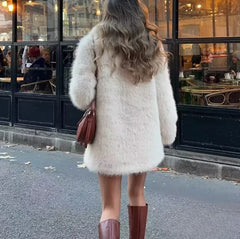 back view of a woman in a cream faux fur coat and brown boots