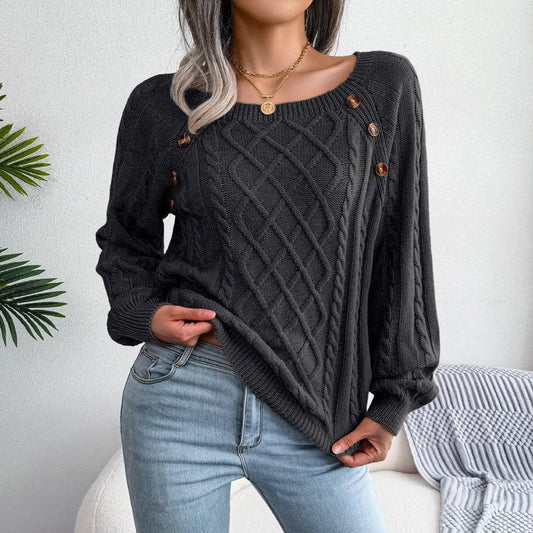Woman wearing a charcoal grey cable knit sweater with scoop neck and button details, paired with light wash jeans.