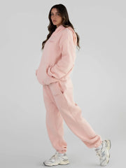 Full body shot of a woman in a light pink tracksuit