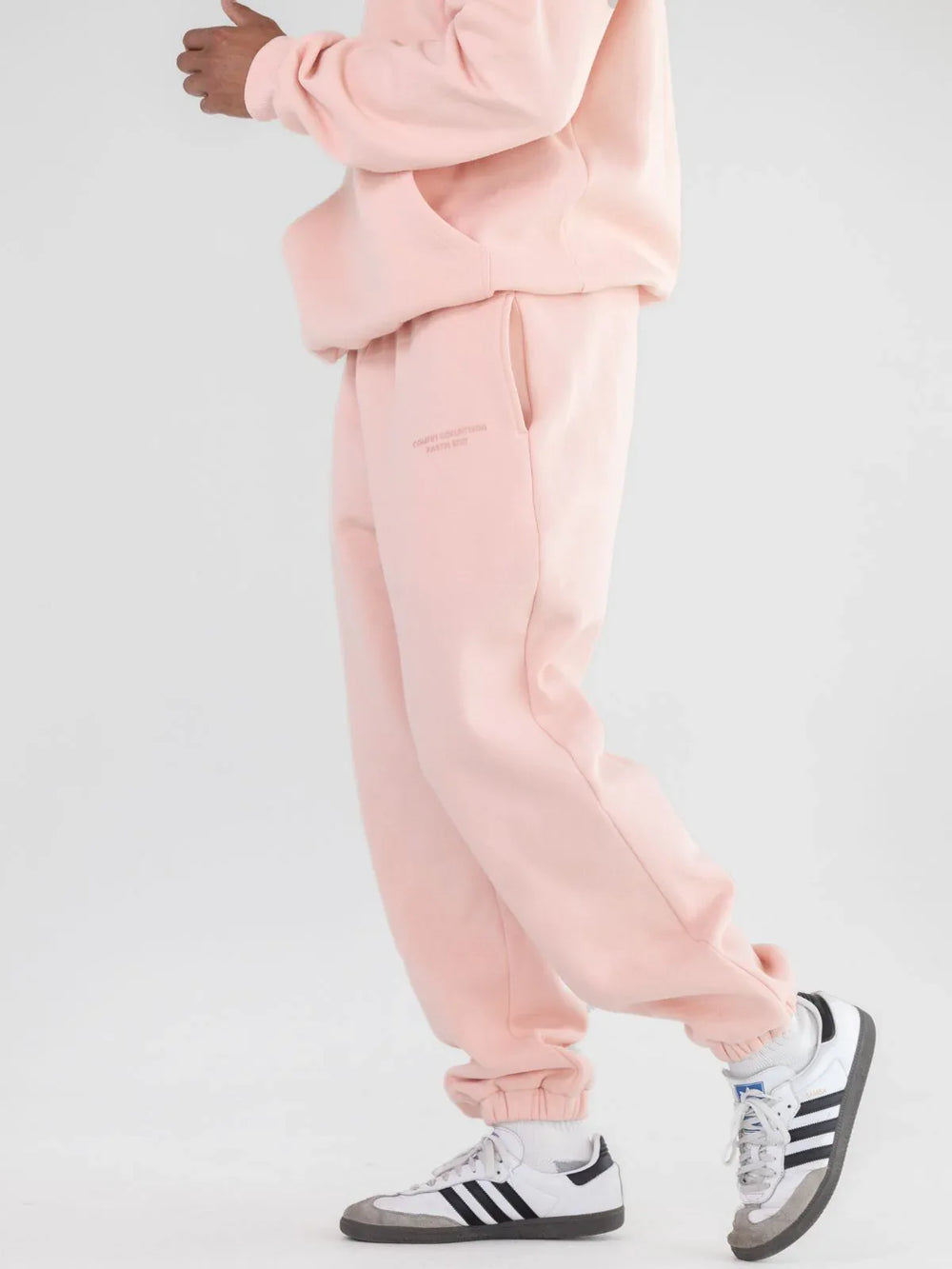 Model wearing light pink sweatpants and white sneakers