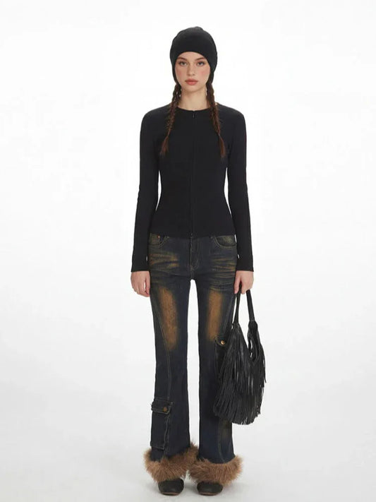 Model wearing a black ribbed knit top, distressed flared jeans with fur trim cuffs, and a black beanie, holding a fringe detail bag.