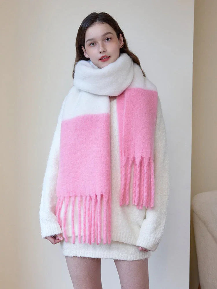 Woman wearing a white sweater and a white and pink two-tone fuzzy knit scarf with fringe trim.