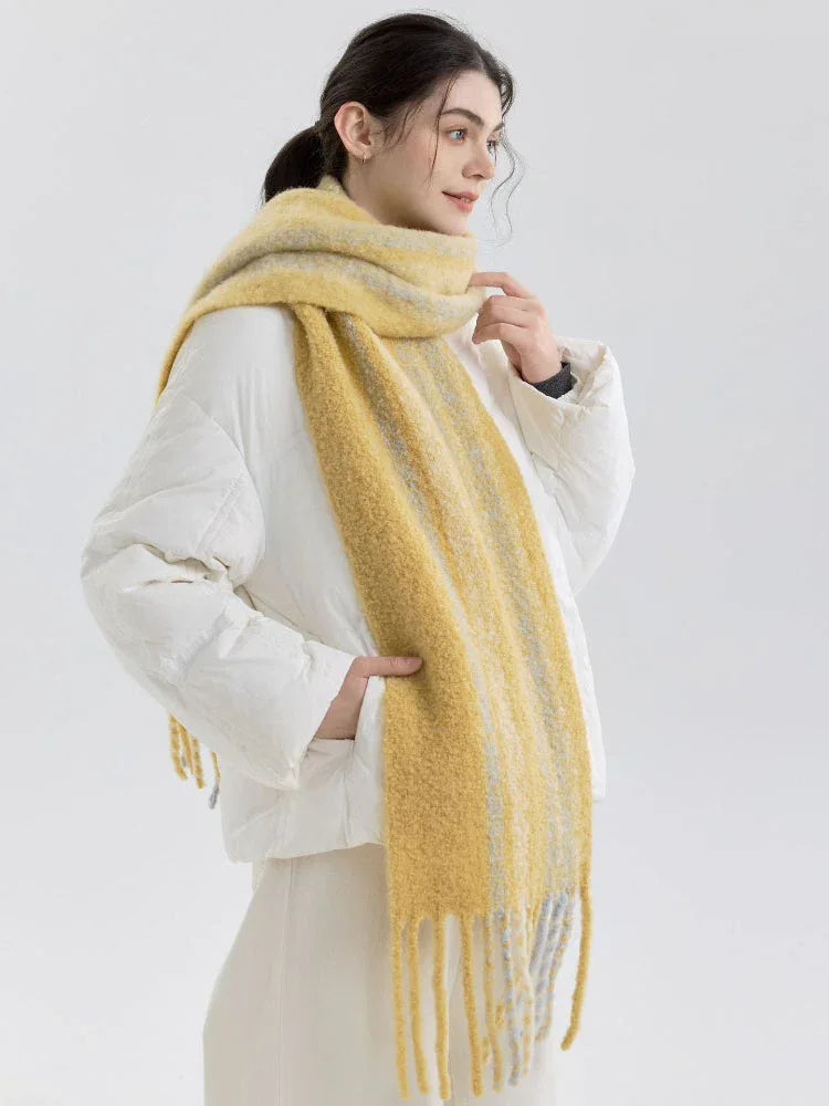 Woman wearing a yellow and gray striped scarf with fringe detail over a white puffer jacket