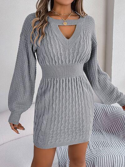 Woman wearing a grey cable knit sweater dress with a keyhole neckline and bishop sleeves.