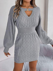 Woman wearing a grey cable knit sweater dress with a keyhole neckline and bishop sleeves.