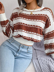 Close-up of a woman wearing a brown and white striped cropped knit sweater and light wash jeans.