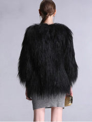 Back view of a woman wearing a black faux fur cropped jacket and a grey knit dress.