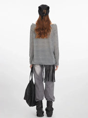 Front view of a woman wearing a black and white striped long-sleeved shirt with an off-the-shoulder neckline.
