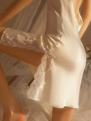 Close-up of a cream-colored satin slip dress with lace trim on the hem and side slit.