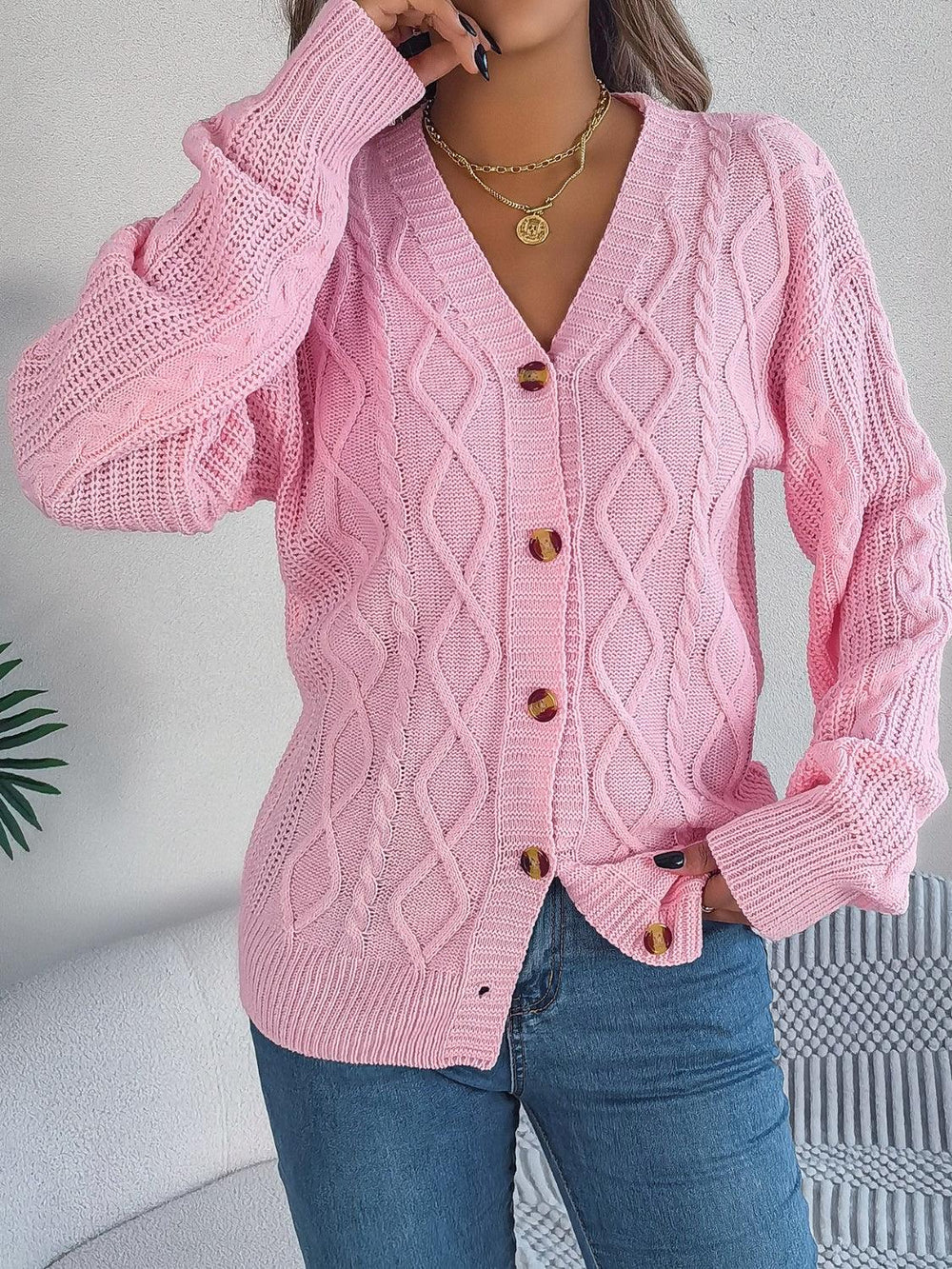 front view of a woman adjusting her pink cable knit cardigan