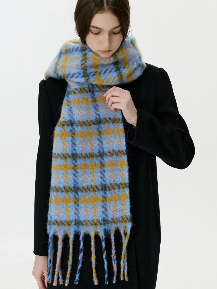 Woman adjusting a blue and yellow plaid scarf with fringe