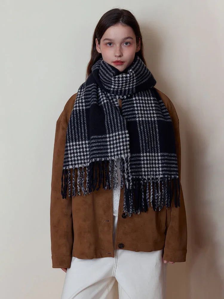 Woman wearing a black and white plaid scarf with fringe detail over a brown jacket