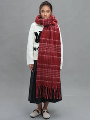 Full body shot of a woman in a white sweater and dark skirt, accessorized with a large red plaid scarf.