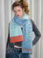 Model wearing a blue and light blue scarf with orange trim and text.