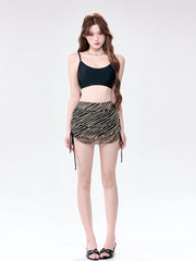Woman wearing a black camisole and a striped ruched mini skirt.