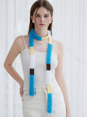 Model wearing a white ribbed tank top and off-white pants with a long, fluffy, color-blocked scarf in blue, yellow, white, and brown.