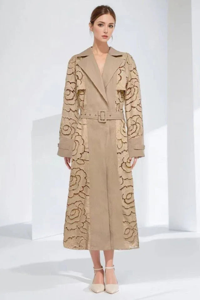 Model wearing a tan laser-cut floral trench coat with a belted waist and notched lapels.