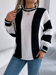 Close-up of a woman wearing a black and white striped knit sweater and blue jeans, touching her hair.