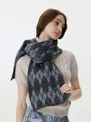 Woman touching her cream cable-knit sweater and a grey and black argyle scarf