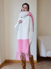 Woman wearing a white sweater and a long white and pink two-tone fuzzy knit scarf with fringe trim, draped to one side.