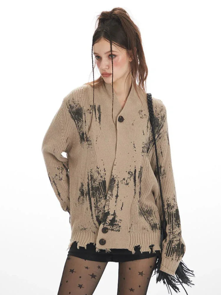 Close-up front view of a model wearing a distressed knit cardigan with a graphic print, focusing on the texture and pattern.