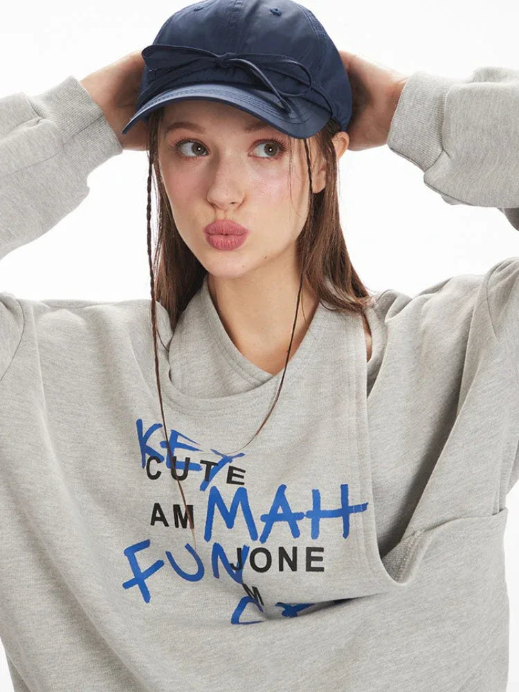 Close-up of model wearing a grey graphic print sweatshirt, making a kissing face