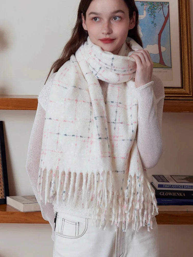 Woman adjusting a white plaid scarf with fringe detail
