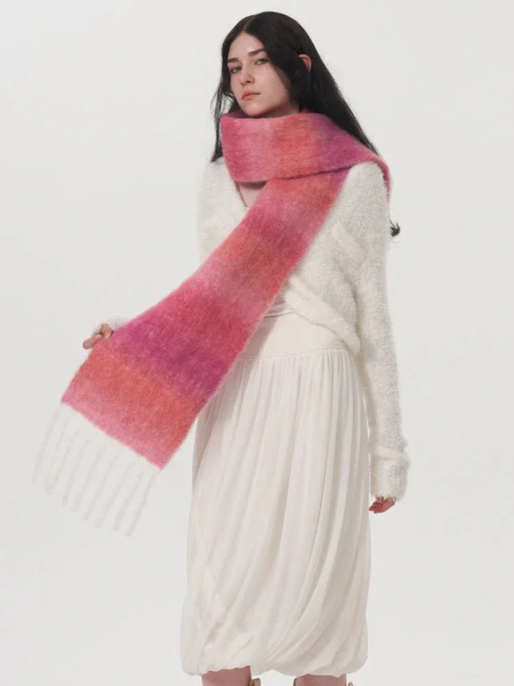 Woman wearing a white dress and a pink and orange gradient scarf with fringe detail.