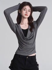 Model wearing a grey long-sleeved top with a draped neckline and a black underlayer.
