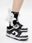 Close-up of black ankle socks with white 3D plush bunny embellishments and white sneakers
