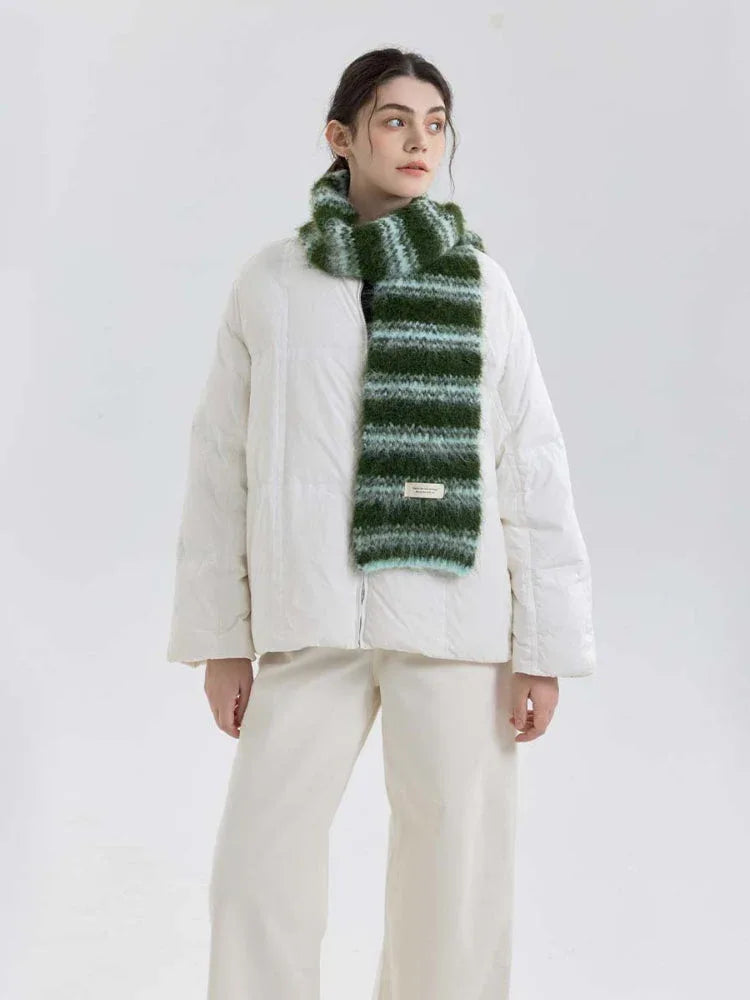 Full body shot of a model in a white puffer jacket and a green and blue striped scarf.