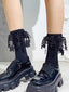 Close-up of feet wearing black ankle socks with intricate lace and star embellishments, paired with chunky black platform shoes.