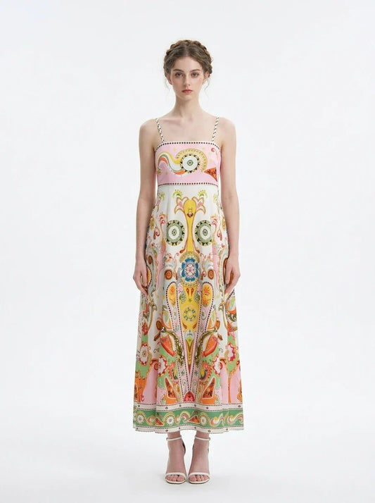 Woman wearing a white maxi dress with a colorful paisley print and pink smocked bodice, standing against a white background.