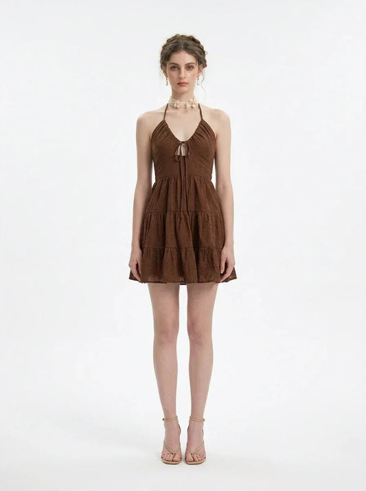 Woman wearing a brown tiered mini halter dress, front view