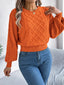 Woman wearing an orange cable knit sweater with blue jeans