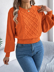 Woman wearing an orange cable knit sweater with blue jeans