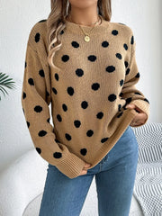 Woman wearing a brown polka dot sweater with blue jeans, front view.