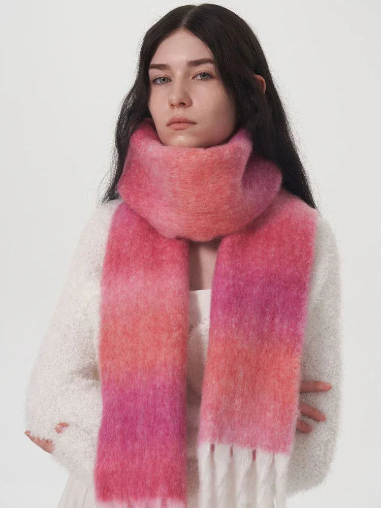 Woman wearing a white sweater and a pink and orange gradient scarf with fringe detail.