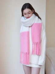 Woman wearing a white sweater and a white and pink two-tone fuzzy knit scarf with fringe trim, looking down.