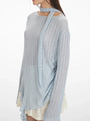 close-up side view of a model wearing a light blue sheer knit sweater with an asymmetrical hem and a neck scarf, paired with a white lace skirt and white heels, holding a white handbag