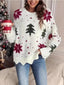 Woman wearing a white knitted sweater with a Christmas tree and snowflake print, holding a red and white coffee cup.