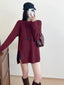 Woman wearing a burgundy ribbed knit longline tunic with side slits and buttons, black shorts, and brown boots, holding a phone to take a mirror selfie.