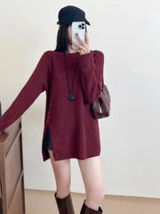 Woman wearing a burgundy ribbed knit longline tunic with side slits and buttons, black shorts, and brown boots, holding a phone to take a mirror selfie.